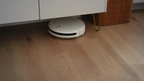 White robot vacuum cleaner working under furniture Stock Footage 303484087