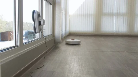 White robotic vacuum cleaner and robot window cleaner work together. Smart Stock Footage 129341829