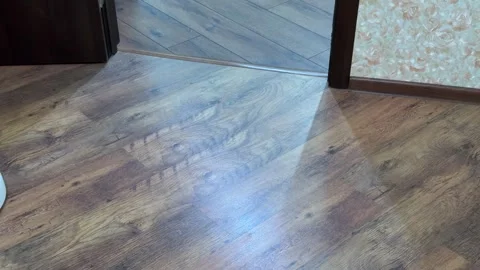 White robotic vacuum cleaner autonomously moving across a wooden laminate floor Stock Footage 321700679