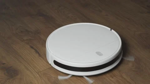 White robotic vacuum cleaner on laminate floor cleaning dust in living room Stock Footage 143832008