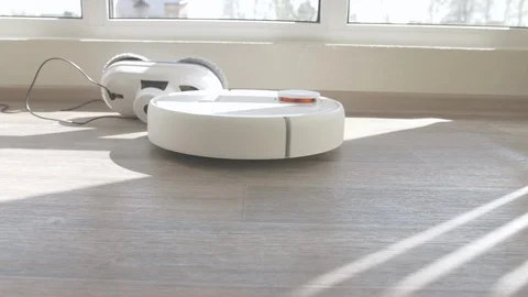 White robotic vacuum cleaner on linoleum wood floor smart cleaning technology Stockbeeldmateriaal 129335308