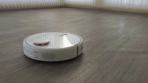 White robotic vacuum cleaner on linoleum wood floor smart cleaning technology Stock Footage 129344070