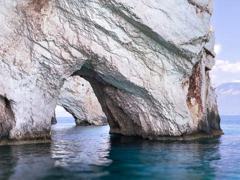 A white rock archway frames the blue water of the Ionian Sea on a sunny day Stock Photos