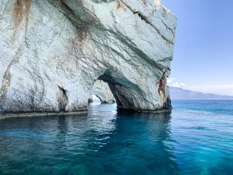 A white rock archway frames the blue water of the Ionian Sea on a sunny day Stock Photos