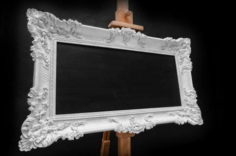 White rococo frame on easel with black copy space. Black background. Stock-Fotos