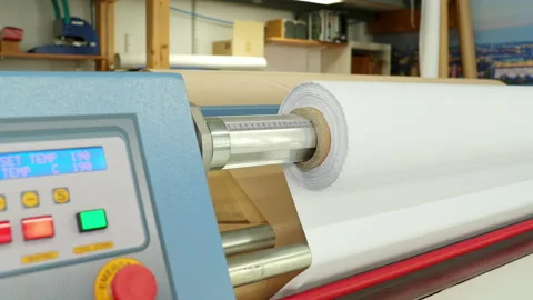 A white roll of fabric rotates on a calender. In the background you can see the Stock Footage 163077206