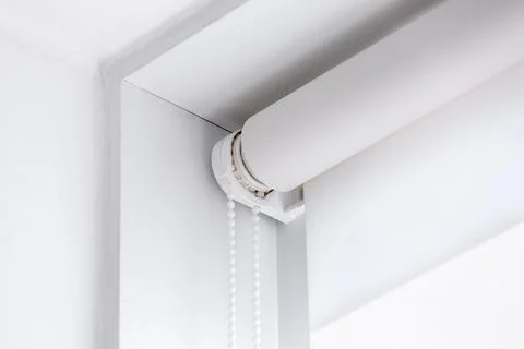 White rolled textile blinds on the window in a room corner. Stock Photos