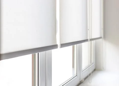 White roller blinds are pulled down over a window close-up Foto stock