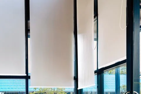 White roller blinds installed on large windows of modern room. .Inside view.. Stock Photos