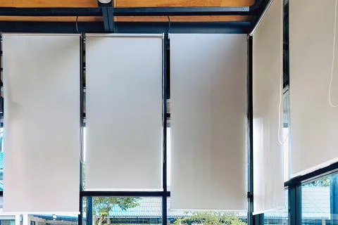 White roller blinds installed on large windows of modern room. .Inside view.. Stock Photos