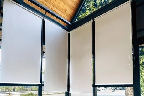 White roller blinds installed on large windows of modern room. .Inside view.. Stock Photos