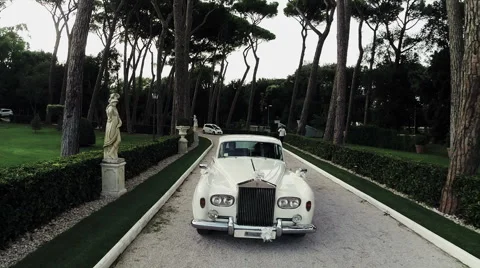 White Rolls Royce walking down the street surrounded by greenery. Aerial drone N Stock Footage 63635410