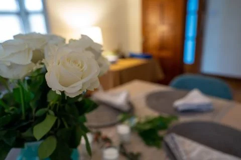 White roses in a case on a simple table setting in home living room Stock Photos