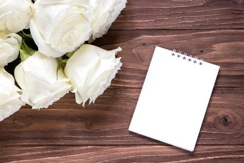 White roses with empty white paper on the wooden table. Original romantic Foto stock