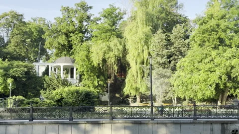 White rotunda stands gracefully in a lush green city park embankment Stock Footage 336936757