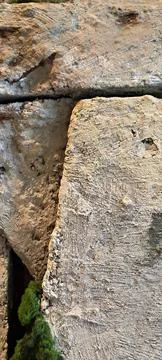 White rough stone wall texture with green moss in crevices 스톡 사진