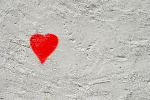 White rough wall with a small red painted heart Stockfoto's