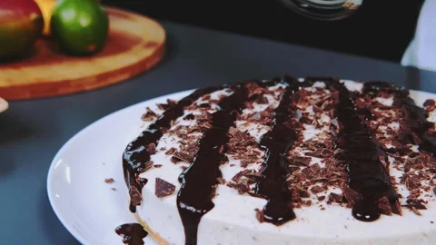 White round cake drizzling melted chocolate sauce indoors on wooden table Stock Footage 342841097