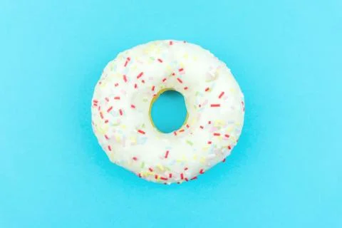 White round doughnut on blue background. Flat lay, top view. Stock Photos