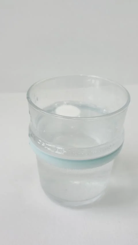 White round effervescent tablet dissolving in a glass of water on a white b.. Stock Footage 335141670