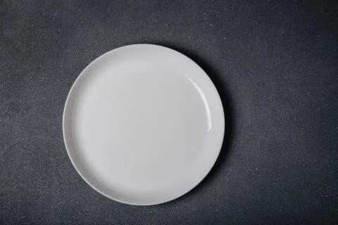 White round empty plate on dark grey background, top view, copy space. Fotos de archivo