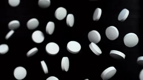White round pills fly up and hover in the air on a black background Stock Footage 141184624