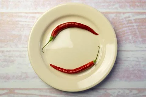 White round plate with two red peppers Stock Photos