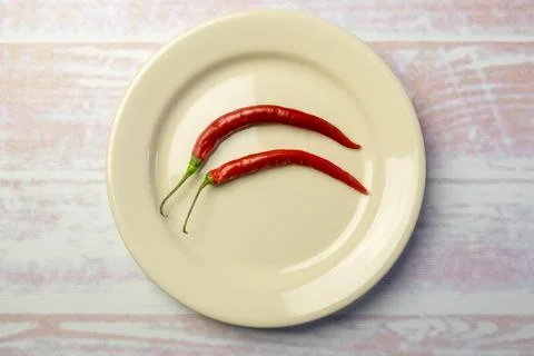 White round plate with two red peppers Stock Photos