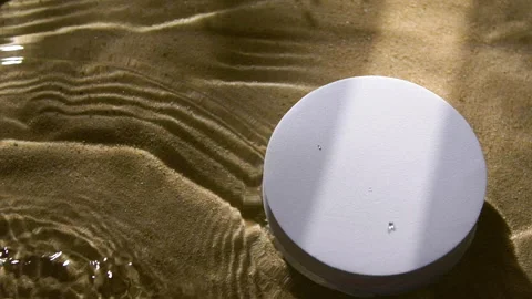 White round podium on sand and water wave, ripple, splash and tree leaf shadow Vídeo Stock 253845658