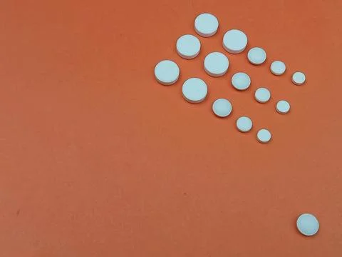 White round tablets arranged in pattern on orange background Stock Photos