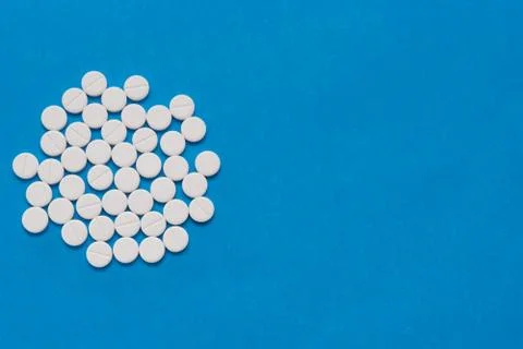White round tablets on a blue background. Macro of white capsules on blue bac Stock Photos