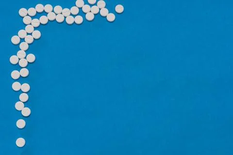 White round tablets on a blue background. Macro of white capsules on blue bac Stock Photos