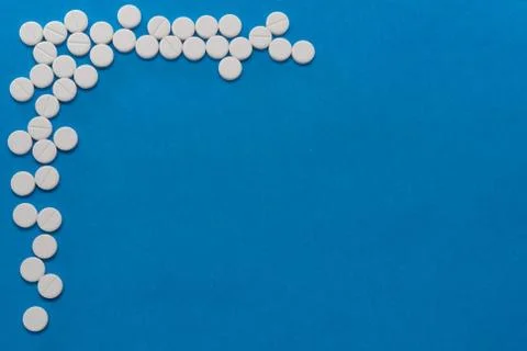 White round tablets on a blue background. Macro of white capsules on blue bac Stock Photos