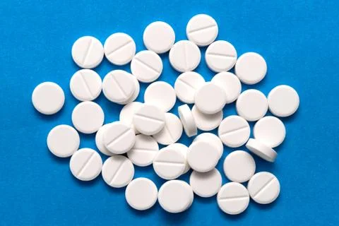 White round tablets on a blue background. Macro of white capsules on blue bac 写真素材