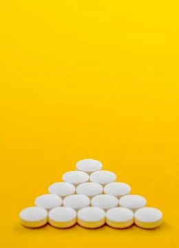 White round tablets stacked in a pyramid shape on yellow background 写真素材
