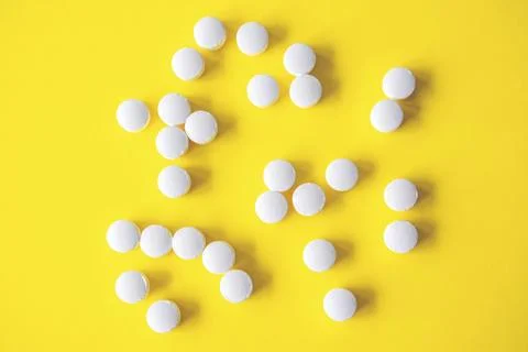White round tablets on yellow background, top view Stock Photos