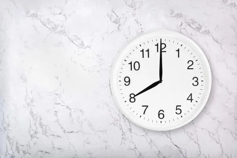 White round wall clock on marble background. Eight o'clock. 스톡 사진