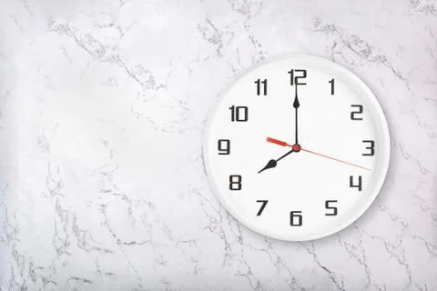 White round wall clock on white natural marble background. Eight o'clock Stock Photos