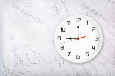 White round wall clock on white natural marble background. Nine o'clock Stock Photos