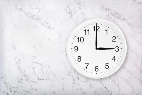 White round wall clock on white marble background Stock Photos