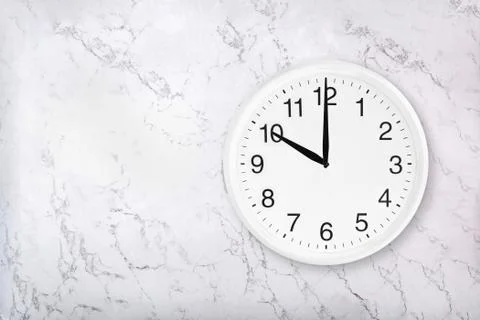 White round wall clock on white marble background Stock Photos