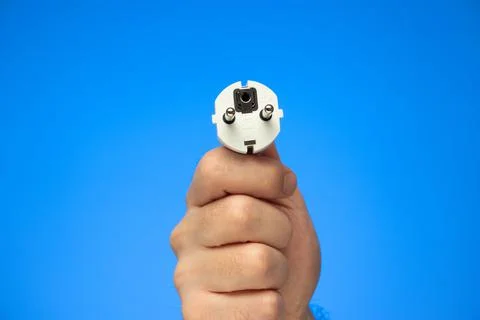 White rubber electrical plug held in hand by Caucasian male hand isolated on  Stock Photos