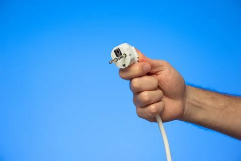 White rubber electrical plug held in hand by Caucasian male hand isolated on  Fotos de archivo