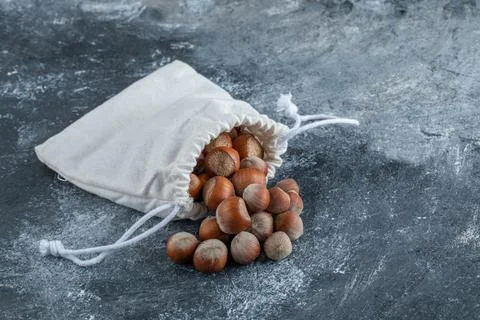 A white sack full of healthy walnuts on a gray background Stock Photos