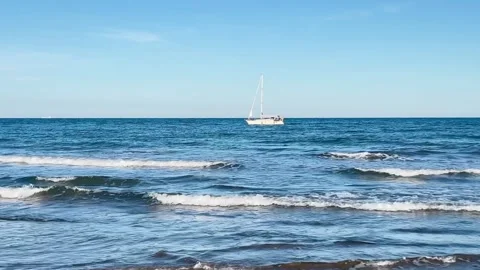 White sailboat drifting on blue open sea on under clear sky Stock Footage 310048891
