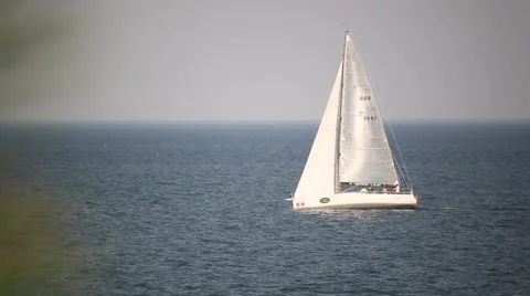White sailboat floats through the frame in the sea Stock Footage 59998397
