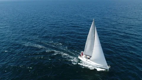 A white sailboat is moving fast on waves of sea. Flying above a boat in ocean. Stockbeeldmateriaal 146606836