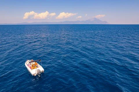 White sailing boat making it's way towards Mt Athos. Calm sea. Beautiful sky Stock Photos