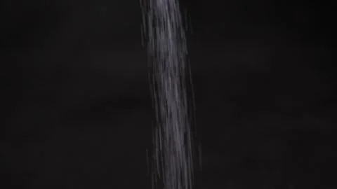 White salt falling on a black surface Stock Footage 160560592
