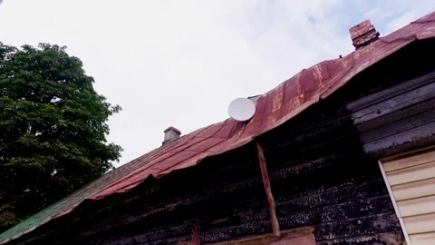White satellite dish antenna installed on rusty corrugated tin roof of Vídeo Stock 344356781